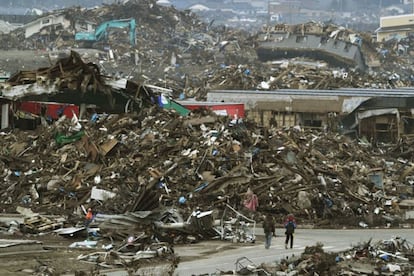 Personas caminan a través de un area llena de escombros cerca de la costa donde se produjo el tsunami en la ciudad de Sendai.