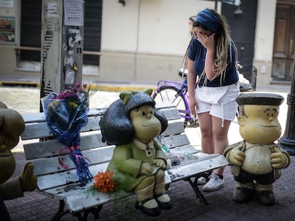 Una mujer llora este miércoles mientras deja flores en la estatua de los personajes de Quino en Buenos Aires.