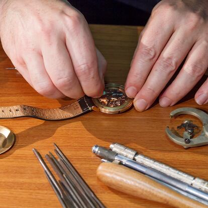 Las manos de una persona reparando un reloj de pulsera.