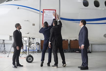 Employees put up a sign on a Venezuelan airplane that was seized in Dominican Republic while Marco Rubio watches on.