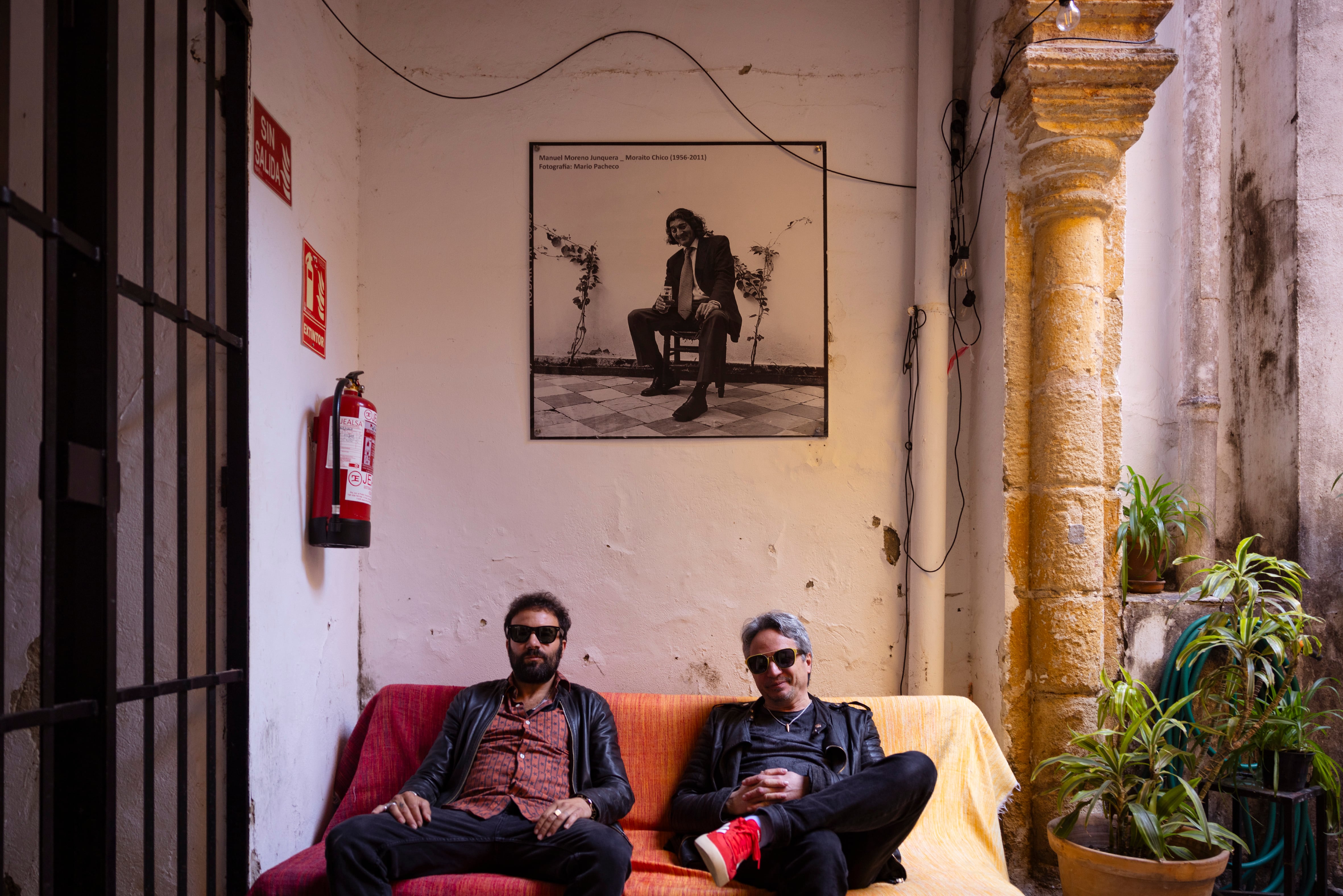 Los dos componentes de Los Delinqüentes a la entrada del bar Damajuana, a las puertas del estudio La Bodega, en Jerez, donde se han grabado todos los discos del grupo. En la pared, una foto realizada por Mario Pacheco del guitarrista jerezano Manuel Moreno Junquera 'Moraíto Chico'. 