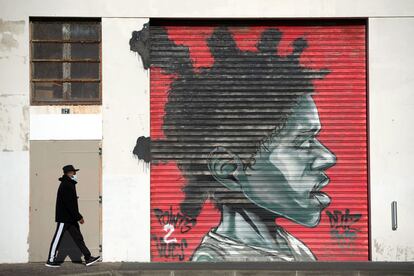 Una persona camina al lado de un grafiti en la ciudad francesa de Bayona.