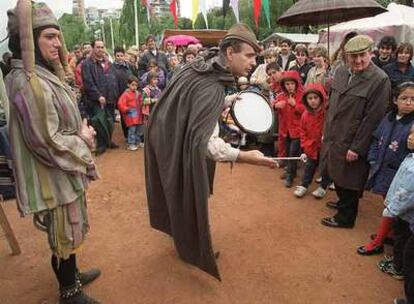 Unos niños conversan con uno de los actores de mercado medieval.