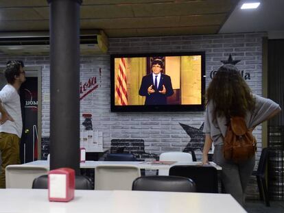 Varias personas escuchan el mensaje del presidente de la Generalitat, Carles Puigdemont.