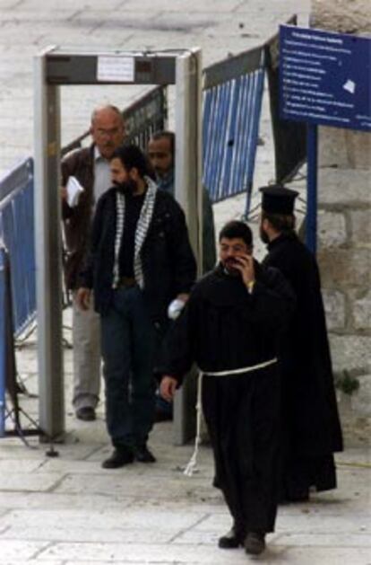 Los primeros palestinos salen de la basílica y pasan por el detector de metales del ejército israelí.