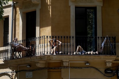 Tres jóvenes toman el sol este viernes en el balcón de su piso del barrio del Eixample de Barcelona.