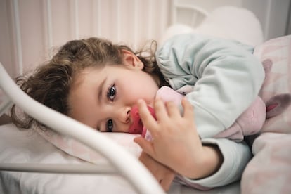 Una niña duerme descansa en su cama.