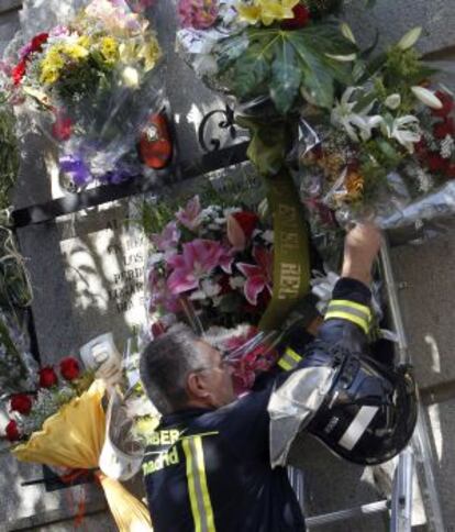 Un bomberos coloca un ramo de flores junto a la placa.
