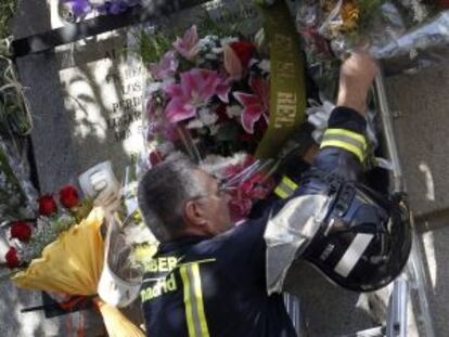 Un bomberos coloca un ramo de flores junto a la placa. 