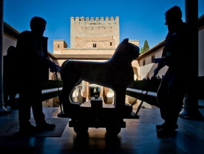 Two operators maneuver one of the restored lions back towards its place around the Court of the Lions fountain.