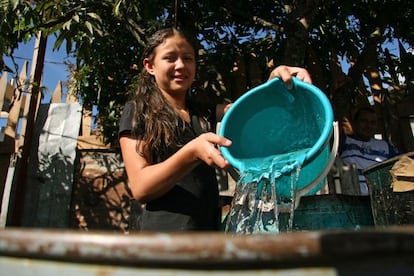 Menina enche um recipiente com água em Honduras.