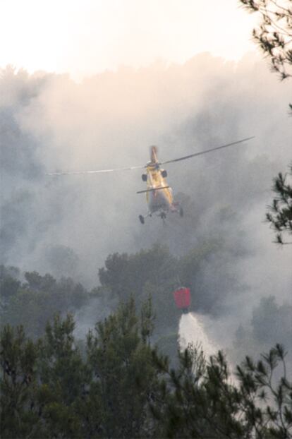 Un avión arroja agua sobre la zona del fuego.