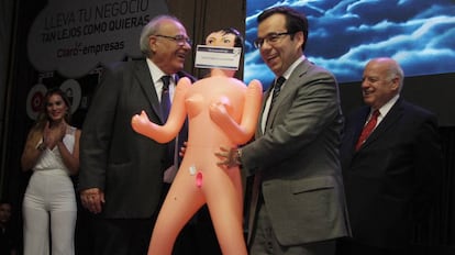 Economy Minister Luis Felipe Céspedes (r) accepts the inflatable doll.