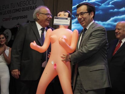 Economy Minister Luis Felipe Céspedes (r) accepts the inflatable doll.