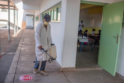 Un empleado desinfecta el suelo de un colegio en Rabat el 8 de septiembre mientras los alumnos atienden a la profesora en una clase.
