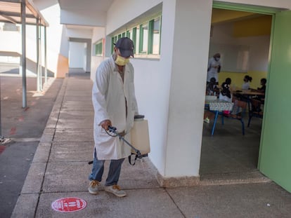 Un empleado desinfecta el suelo de un colegio en Rabat el 8 de septiembre mientras los alumnos atienden a la profesora en una clase.