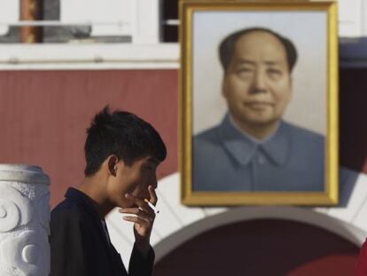 Un hombre fuma un cigarrillo delante de una imagen de Mao Zedong, este viernes en Yinchuan. 