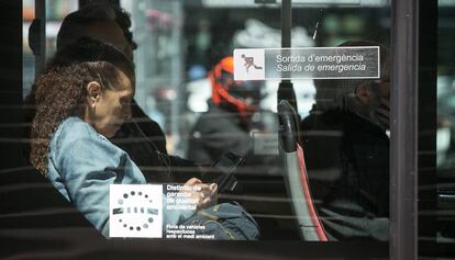 Una pasajera utiliza su teléfono móvil en un autobús público de Barcelona