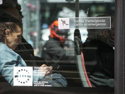 Una pasajera utiliza su tel&eacute;fono m&oacute;vil en un autob&uacute;s p&uacute;blico de Barcelona
