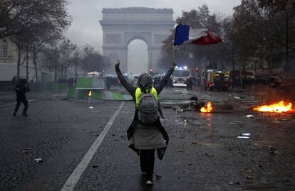 Uno de los 'chalecos amarillos' con una bandera francesa camina hacia el Arco del Triunfo, durante las protestas de este sábado.