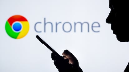 El logotipo de Google Chrome en el fondo de una silueta de mujer que sostiene un teléfono móvil.