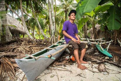 Un joven pescador junto a su canoa.