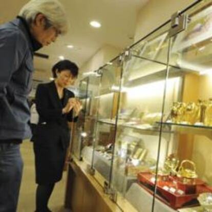 Un hombre japonés observa una vitrina con objetos de oro en una agencia de venta de oro en Tokio