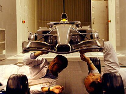 Dos mecánicos trabajan en el prototipo del 50% del coche real que se encuentra ubicado en el túnel de viento de Enstone, en Inglaterra.