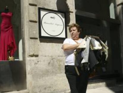 María Luisa Trives sale de la tienda de la firma Hannibal Laguna en Alicante con parte de los trajes que le han entregado tras la ejecución de un embargo por las deudas que el modisto tiene con la que fue su trabajadora durante 13 años y a la que le debía el sueldo los últimos dos años y medio.