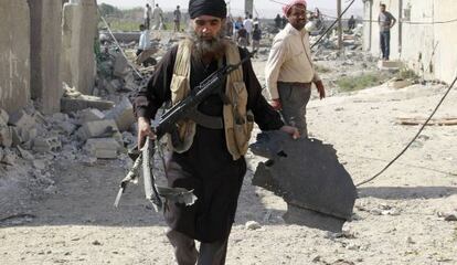 Un miembro del EI lleva un pedazo de un avión caído en Raqa (Siria).