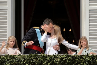 La reina Letizia besa a don Felipe en el balcón del Palacio Real de Madrid, mientras Leonor, princesa de Asturias, y la infanta Sofía saludan a los ciudadanos tras el acto de proclamación celebrado en el Congreso de los Diputados. 