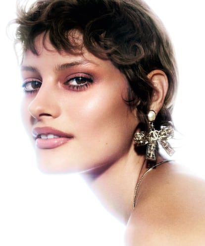 En los ojos, ahumado suave con las sombras de la paleta de Les 4 Ombres, edición Boutons (tono Couture) y máscara de pestañas Le Volume (tono Black). Pendientes y cadena plateados. Todo de CHANEL.