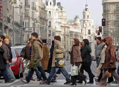 Varias personas cruzan un semáforo en la Gran Vía de Madrid