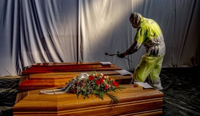 Un militar coloca flores en varios féretros.