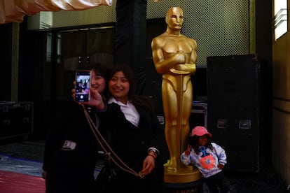 People pose for a picture in front of an Oscar statue near the red carpet arrivals area along Hollywood Blvd as preparations continue for the 96th Academy Awards in Los Angeles, March 8, 2024. 