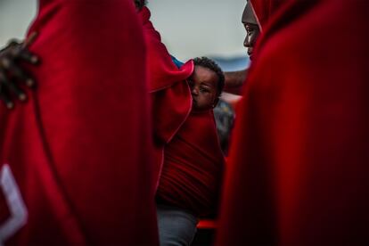 Un bebé llega a espaldas de su madre al puerto de Motril, Granada. Menores, embarazadas y los necesitados de atención sanitaria, tras ser identificados, quedarán en manos del personal de Cruz Roja. En el Aquarius había cien menores no acompañados. Cuando los niños llegan sin familia entran en un sistema de protección con bastantes lagunas, según diferentes ONG, y cuando cumplen 18 años regularizan su situación.