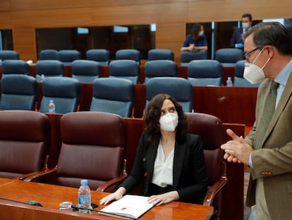 El diputado del PP Alfonso Carlos Serrano habla con Isabel Díaz Ayuso, durante el pleno de este jueves en la Asamblea de Madrid.