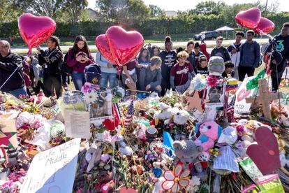 Cruz conseguiu fugir da escola misturado com a multidão que corria, mas foi detido pouco mais tarde. O promotor do Estado de Flórida pediu a pena de morte contra o jovem. Na foto, estudantes do instituto Stoneman Douglas junto aos objetos em lembrança das vítimas, em Parkland, Flórida.