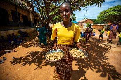 Una maestra lleva alimentos para los alumnos de la escuela primaria de niñas Wau A en Wau, en Sudán del Sur, como parte del Programa de Alimentación del PMA y Unicef.