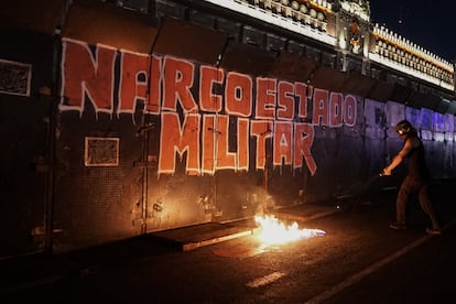 Personas lanzan combustible a un fuego frente a Palacio Nacional, este martes.