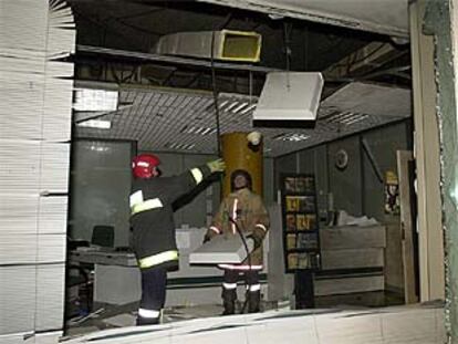 Los bomberos arreglan los desperfectos causados en una de las sucursales bancarias atacadas en Cizur Mayor.