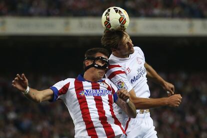 El jugador el Atl&eacute;tico Mario Mandzukic y Grzegorz Krychowiak, del Sevilla, se disputan un bal&oacute;n a&eacute;reo. 