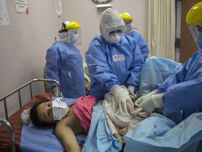 María Álvarez, de 24 años, espera que le entreguen a su bebé recién nacida mientras obstetra y neonatólogo sujetan el cordón umbilical de la recién nacida, en el Instituto Nacional Materno Perinatal en Lima, Perú, el 29 de julio de 2020. Álvarez, un caso asintomático del nuevo coronavirus, dio a luz a su primer hijo en una sala especial para madres infectadas. El padre de la niña murió por la covid-19.