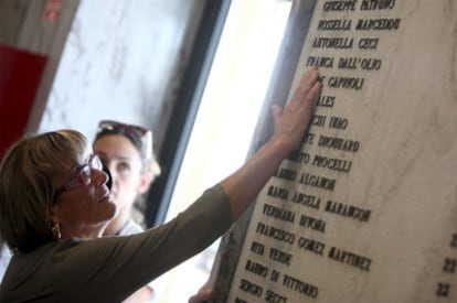 Una mujer mira la placa con los nombres de las 85 víctimas del atentado de Bolonia en el día del 30 aniversario.