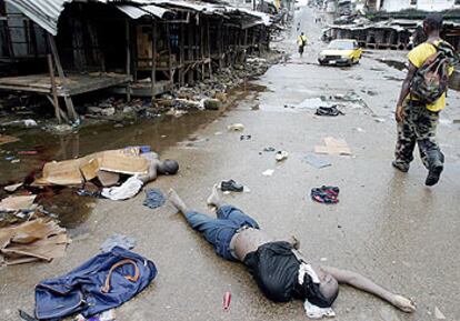 Un soldado gubernamental pasa junto a los cadáveres de dos saqueadores, ayer, en Monrovia.