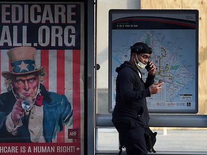 Un hombre mira el móvil al lado de un cartel de Medicare (seguro de salud para mayores en EE UU) en Washington DC.