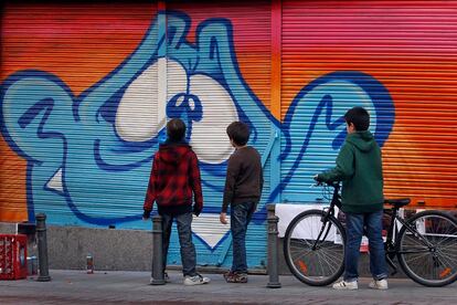 Tres niños del barrio observan una de las pintadas en la calle Corredera Alta de San Pablo.