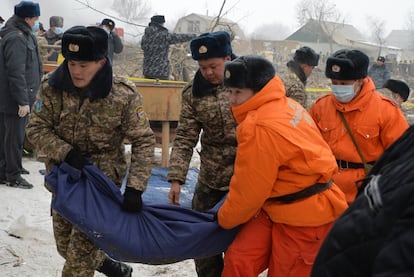 Soldados kirguises y socorristas trasladan el cuerpo de una víctima en el lugar del accidente.