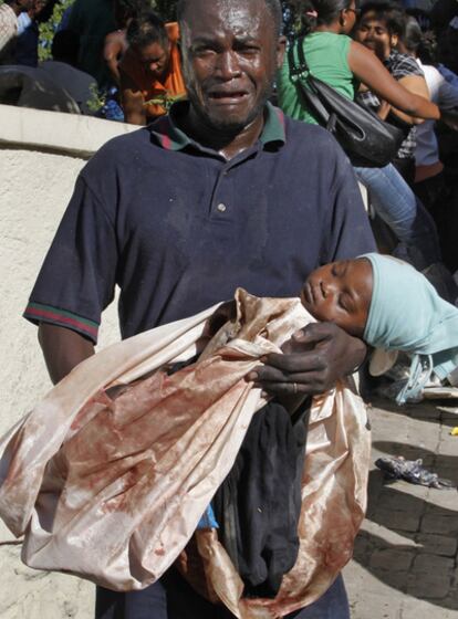 Un hombre herido, con el cadáver de su hija en brazos en Puerto Príncipe.