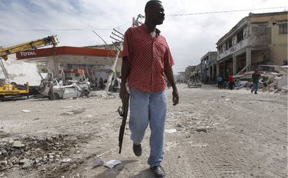 Un hombre armado camina por una calle del centro de Puerto Príncipe vigilando para evitar el saqueo de los comercios destruidos por el terremoto.